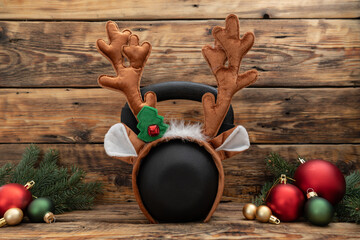 Gym kettlebell in reindeer antlers headband Christmas decoration. Healthy fitness lifestyle holiday...