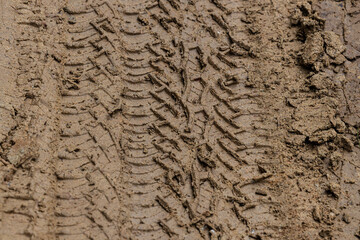 Tire tracks from the wheels of passing cars in the wet, softened ground on a muddy rural road.Multi layers of tire tracks print on dirty brown soil.Wheel marks of cars and trucks on countryside route.