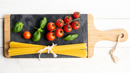 Fresh cherry tomatoes, pasta, basil on slate plate