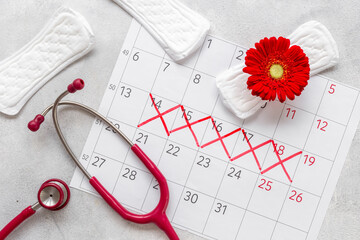 Stethoscope and calendar with red days of menstruation period. Women health