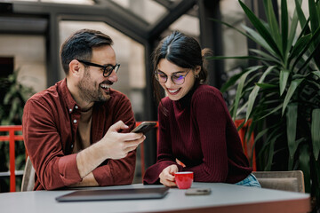 Businessman and businesswoman sitting next to each other, enjoying their break from work.