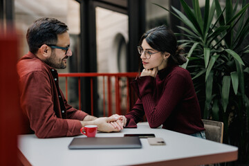 Business couple sitting and talking to each other, holding hands, at the office.