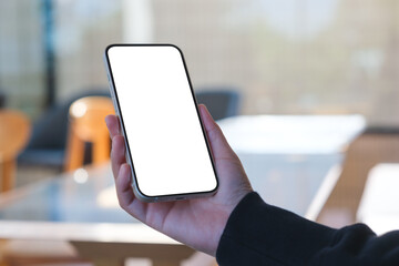 Mockup image of a woman holding mobile phone with blank desktop screen in cafe