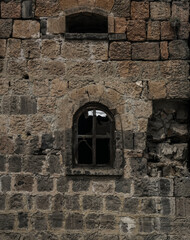 Fototapeta na wymiar architecture background of stone grey wall one Window in a medieval building. front view. brick wall with a old window frame. Stone wall of an old building with two arched windows. Windows are closed