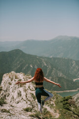 Girl doing yoga on the top of the mountain