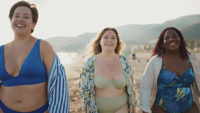 Cinematic storytelling footage of beautiful plus size women having fun at the beach in the summertime. Oversized big girls friends, representation of body positivity and body acceptance concepts