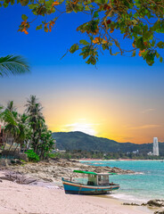Colourful Sunrise over Patong Beach in Phuket Thailand with boat on the beach sand in the foreground