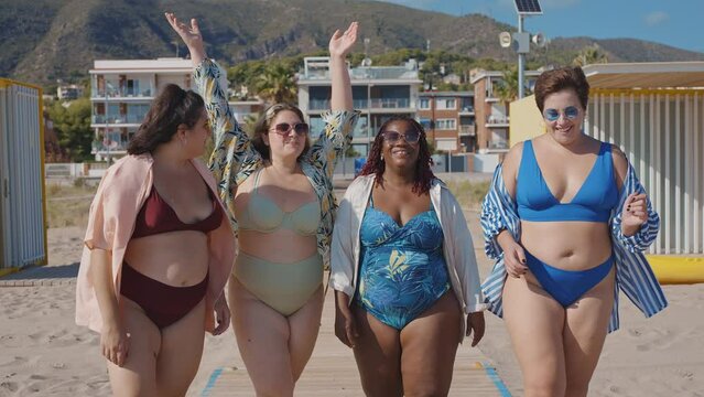 Cinematic storytelling footage of beautiful plus size women having fun at the beach in the summertime. Oversized big girls friends, representation of body positivity and body acceptance concepts
