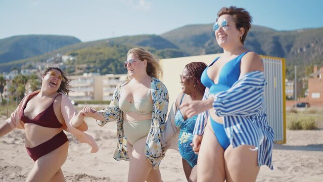 Cinematic storytelling footage of beautiful plus size women having fun at the beach in the summertime. Oversized big girls friends, representation of body positivity and body acceptance concepts