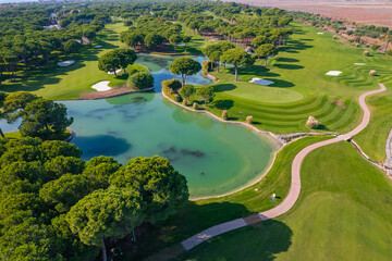 Green golf course luxury field with lake, aerial top view