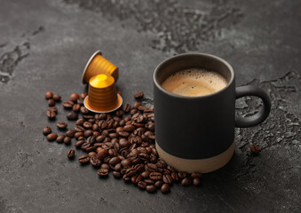 Coffee cup with fresh raw beans and coffee capsules on black background.