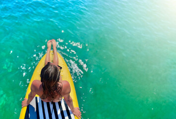 Young beautiful woman relaxing in the sea on a sup board.Top view. Copy space