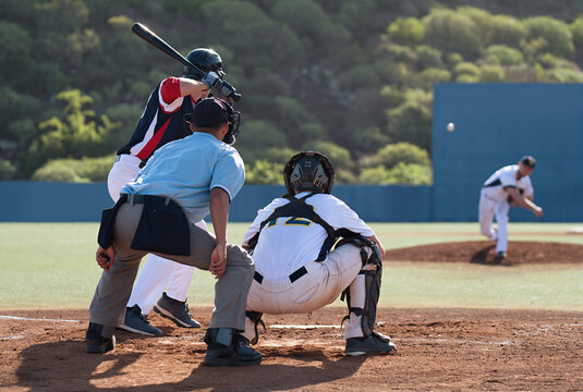 Baseball players in action on the stadium, baseball batter waiting to strike the ball. Baseball pitcher following through to pitch to right handed batter