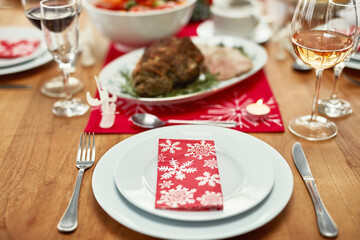 Wine glass, plate and cutlery on the table at a christmas party or event in the dining room of a house. Napkin, table setting and dinner party for a festive xmas holiday lunch celebration at a home.