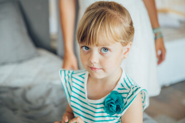 daughter looks at the camera, and mom stands behind. High quality photo