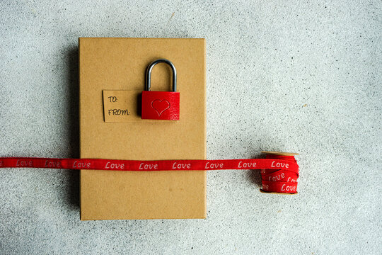 Overhead view of a gift box, a padlock with a heart, gift tag and ribbon with the word love