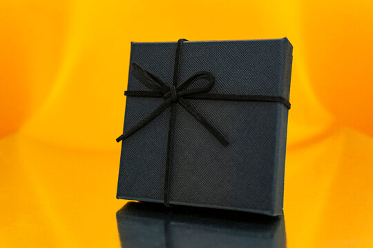 Close-up of a black wrapped gift against an orange background