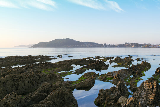 Coastal rock pools and distant view of town, Rias Baixas, Panxon, Nigran, Galicia, Spain