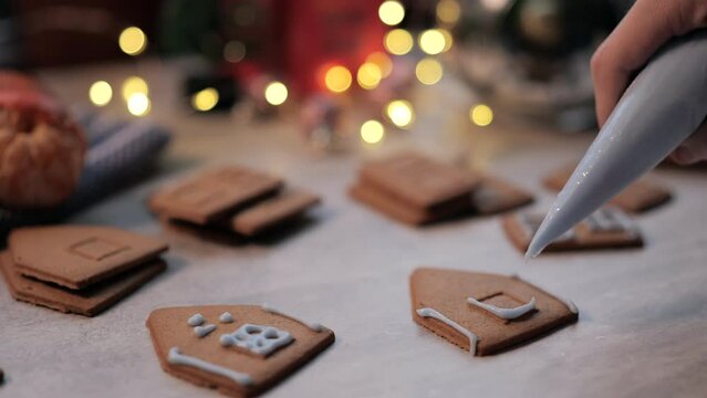 Hand decorates ginger Christmas gingerbread with white glaze