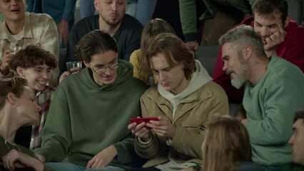 Audience sits at sports event, looking into the phone screen of a spectator instead of the game