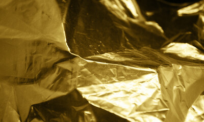 Gold foil background with light reflections. Golden textured wall.