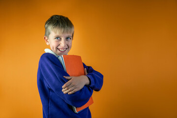 A schoolboy with notebooks, orange background, copy space
