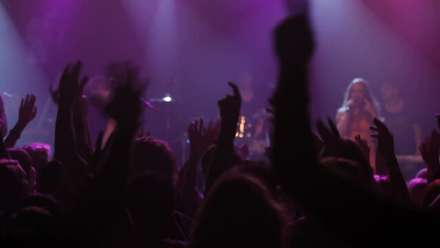 Band, music festival and show with singing, dancing and purple lights for a rock, jazz and live concert in a nightclub. Men and women audience, fans and crowd together for performance at party