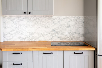 Empty modern minimal grey color kitchen, marble wall, solid natural wood butcher block countertop...