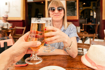 people and vacation concept - close-up of a smiling woman holding a glass of draught lager beer and toasting