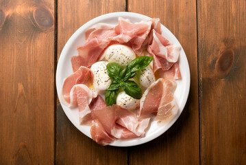 Piatto con deliziosa mozzarella di bufala campana e fette di prosciutto crudo, antipasto italiano 