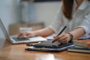 Closeup hand signing or using a digital pen on a computer tablet on the desk, a businesswoman use a stylus pen to write on a tablet