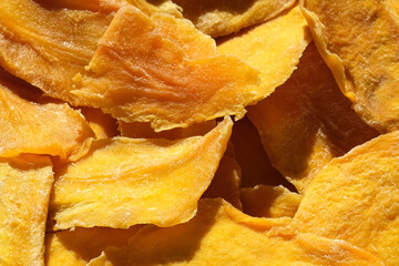 Dried mango slices close-up on a white. Top view. Closeup. Mango chips background. Dehydrated...