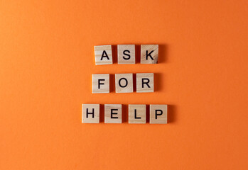 Ask for help word phrase in wooden letters. Motivation and slogan. Orange background.