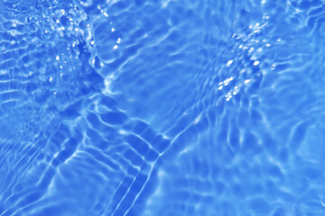Bluewater waves on the surface ripples blurred. Defocus blurred transparent blue colored clear calm water surface texture with splash and bubbles. Water waves with shining pattern texture background.