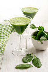 Spinach and cucumber green cocktail on white wooden table