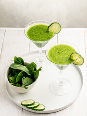 Spinach and cucumber green cocktail on white wooden table