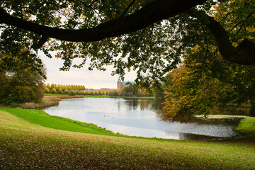Fototapeta na wymiar Frederiksborg Castle Park in autumn with mighty deciduous, landscaped lake.
