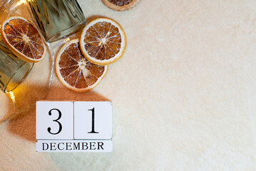 calendar with the date December 31 on a background of oranges, glasses of garland on a beige...