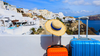 The banner of travel concept with two luggage with hat and landscape view of Oia town in Santorini...