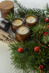 Soy candles burn in glass jars. Comfort at home. Candle in a brown jar. Scent and light. Scented handmade candle. Aroma therapy. Christmas tree and winter mood. Cozy decor. Festive garland decoration