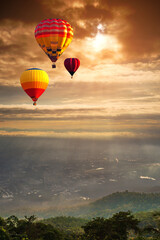 Naklejka premium Colorful balloons floating over big city and mountain, sunset background. Hot air balloon over Chiang Mai City in Thailand. aviation and doi suthep.