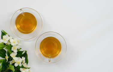 Jasmine tea in a cup and teapot on the table from above, jasmine flowers and dried leaves, herbal tea, healthy food, white background