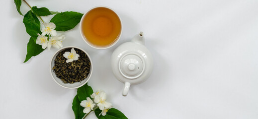 Jasmine tea in a cup and teapot on the table from above, jasmine flowers and dried leaves, herbal tea, healthy food, white background