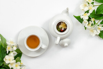 Jasmine tea in a cup and teapot on the table from above, jasmine flowers and dried leaves, herbal tea, healthy food, white background