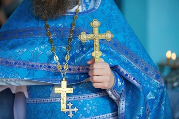 A Christian priest in a church holds a cross in his hands during a religious ceremony.