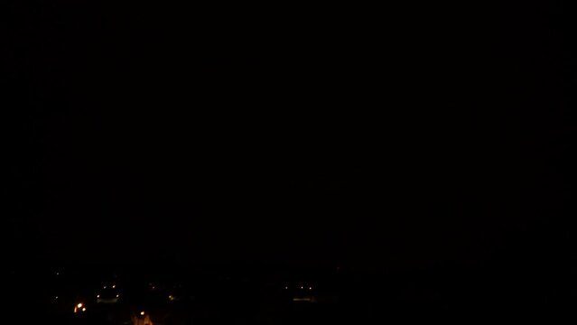 Video &agrave; vitesse r&eacute;elle d'&eacute;clairs d'orage tr&egrave;s rapides qui illuminent les nuages au-dessus d'un petit village dans la nuit noire