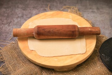 A stretched dough with a rolling pin on a wooden plate