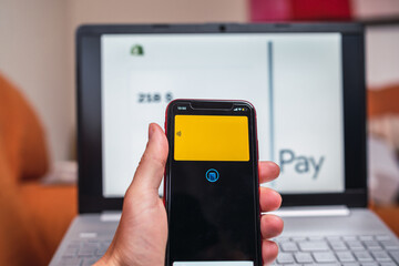 Hand of anonymous person holding his mobile phone to make online purchases with the digitized credit card in an app.