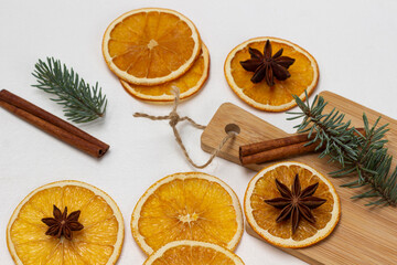 Fototapeta na wymiar Star anise on dry orange slices, cinnamon and sprig of spruce on board and on the table.