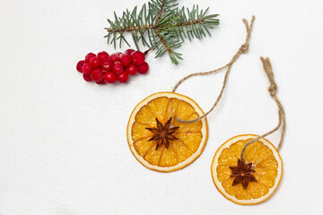 Star anise on dry orange slices, sprig of spruce and red berries on table.